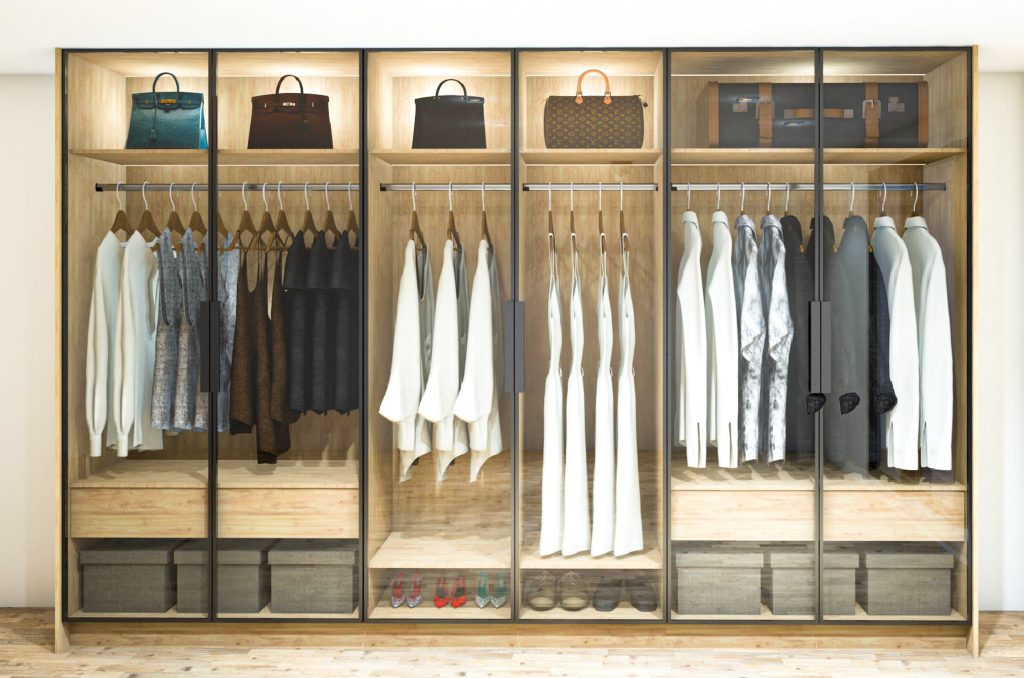 Tinted glass custom wardrobe with wooden grain panel, soft-close system, chrome hanging rails, integrated handles, and LED lighting