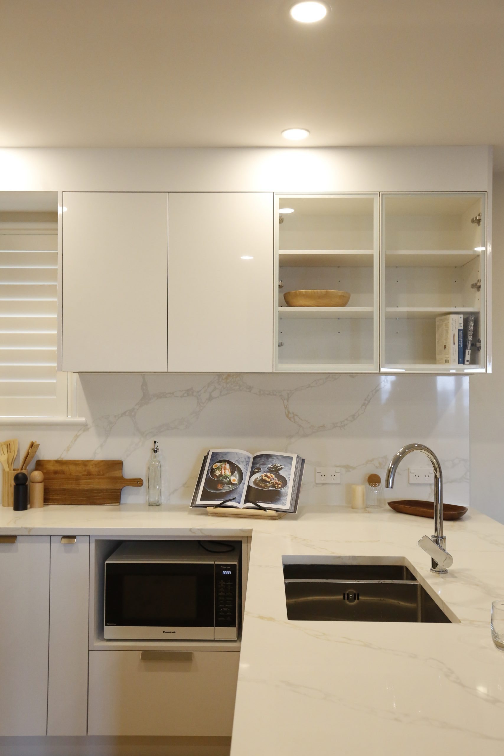 Modern white kitchen with glass door cabinet and white marble engineered stone benchtop
