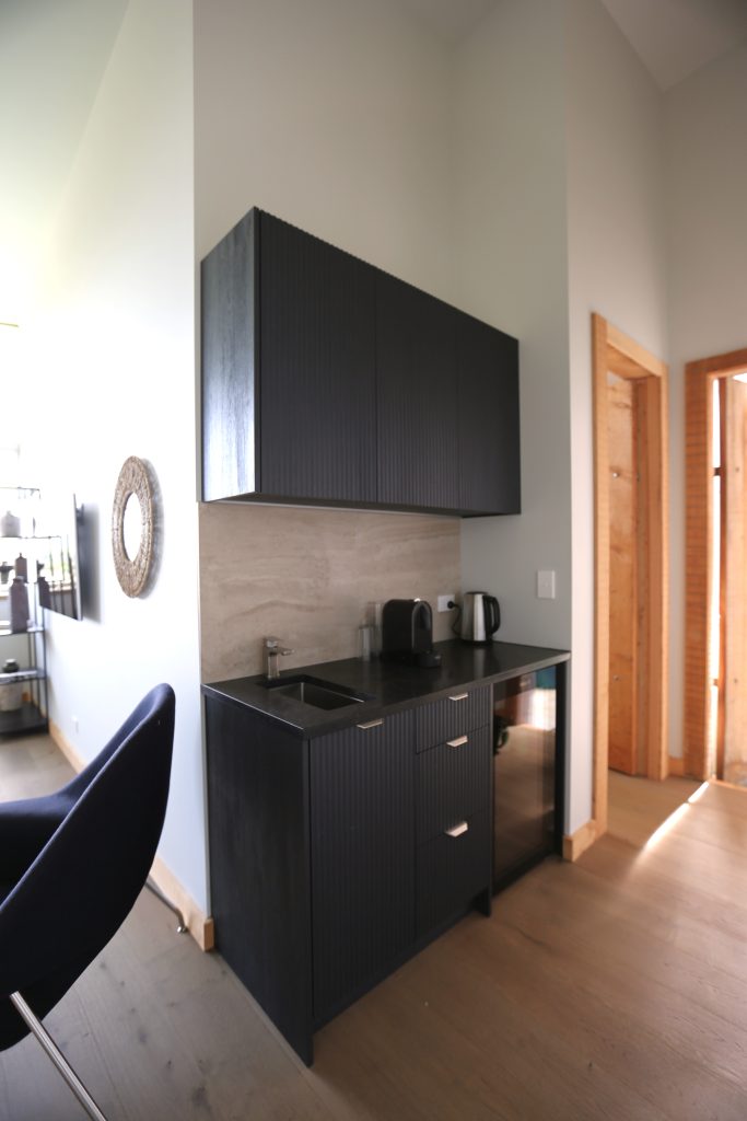 Custom kitchenette with engineered stone benchtop marble-like tile splashback