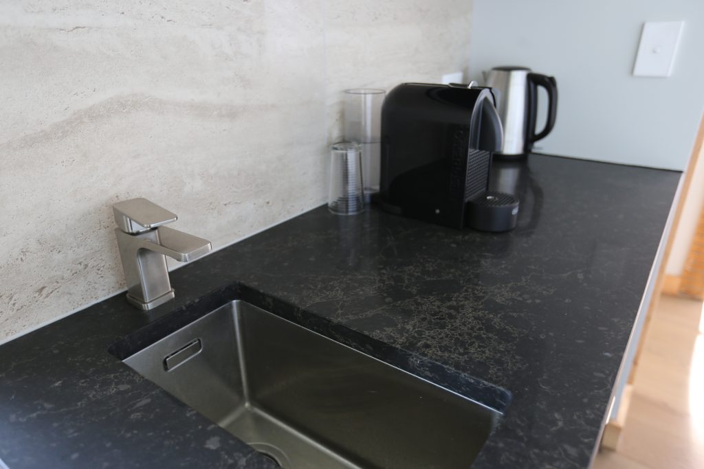Custom kitchenette with engineered stone benchtop marble-like tile splashback