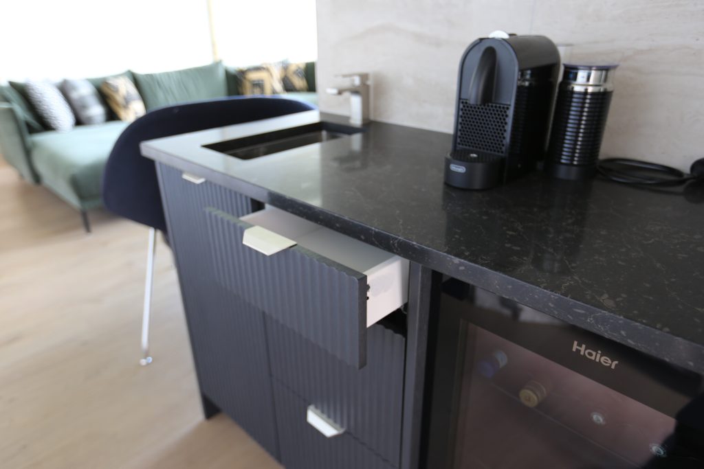 Custom kitchenette with engineered stone benchtop marble-like tile splashback