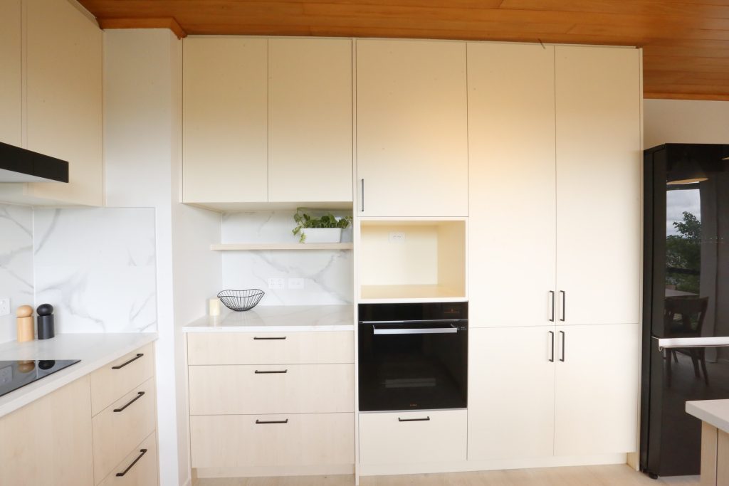 Warm woodgrain open plan kitchen with engineered stone benchtop ad marble veined splashback, kitchen renovation Auckland
